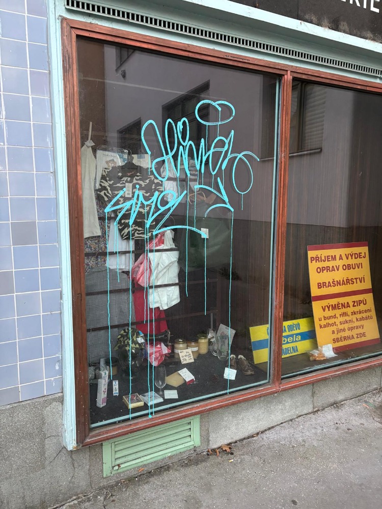 Graffiti tag na skle výkladu predajne pred odstránením